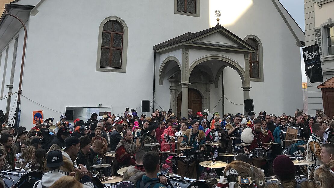 Eine bunte Menge Karnevalisten auf dem Kapellplatz vor der Peterskapelle in Luzern.